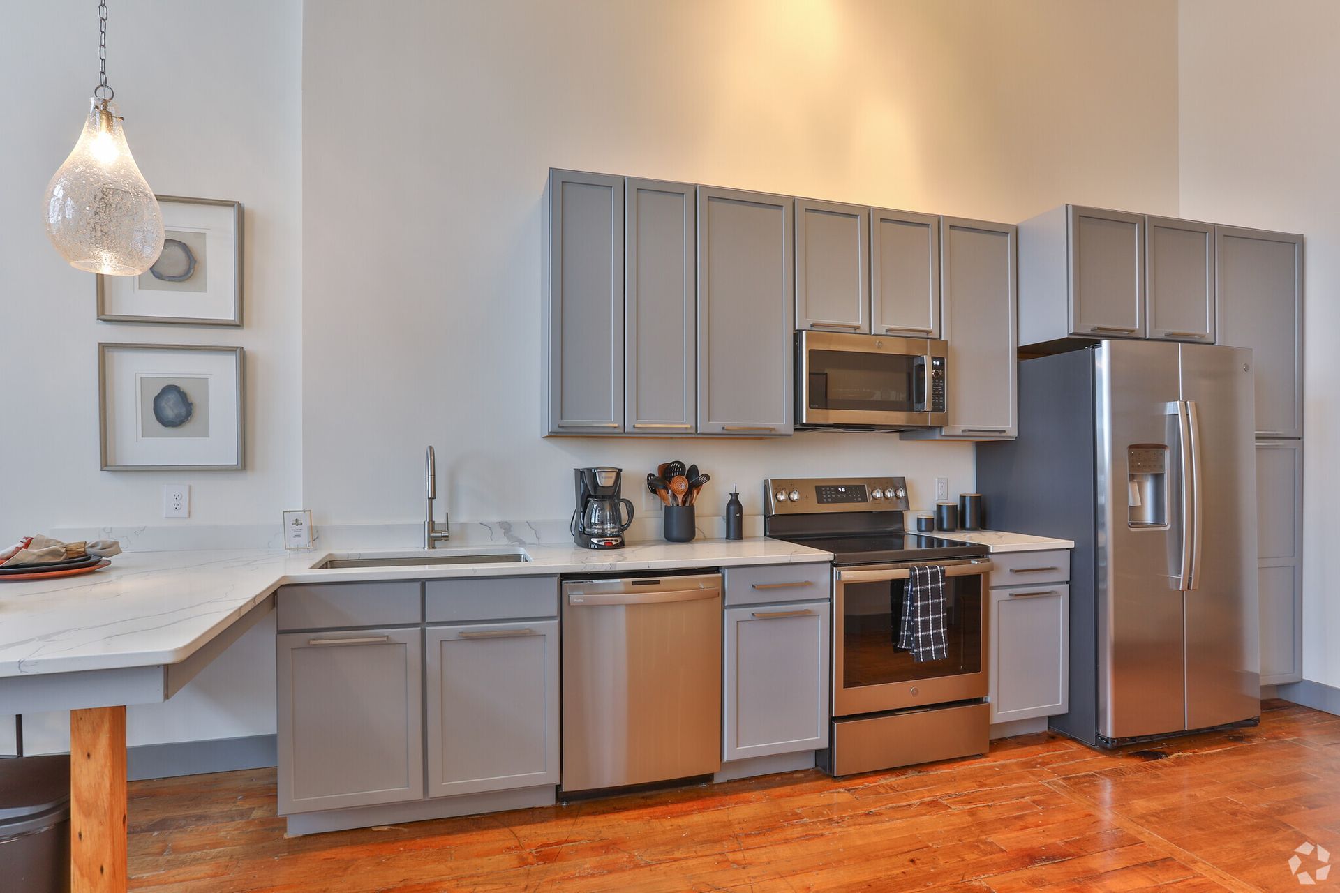 A kitchen with stainless steel appliances and gray cabinets.