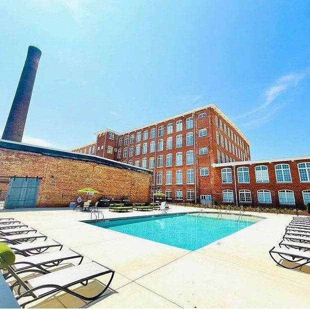 A large brick building with a large swimming pool in front of it.