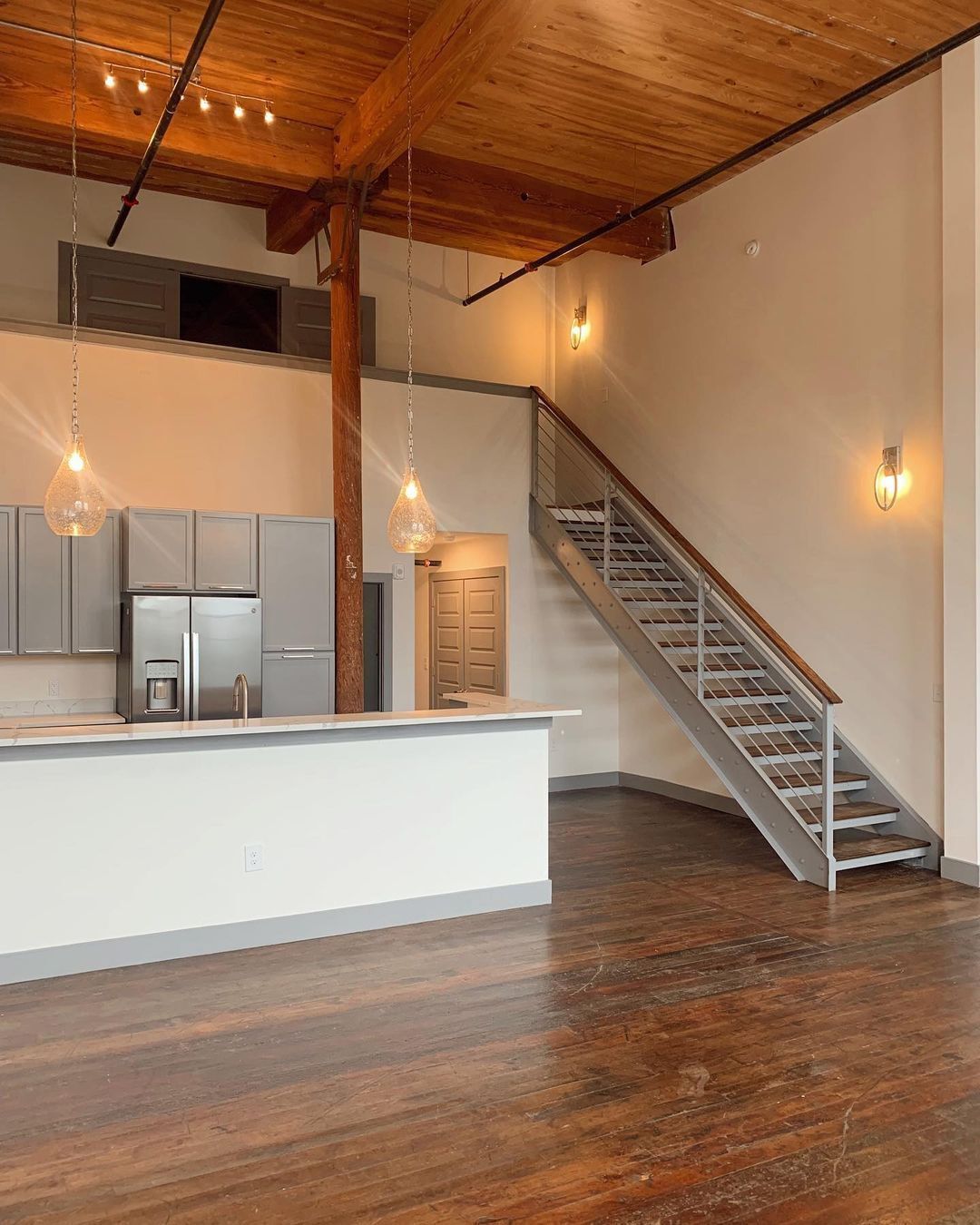 An empty kitchen with stairs leading up to the second floor.