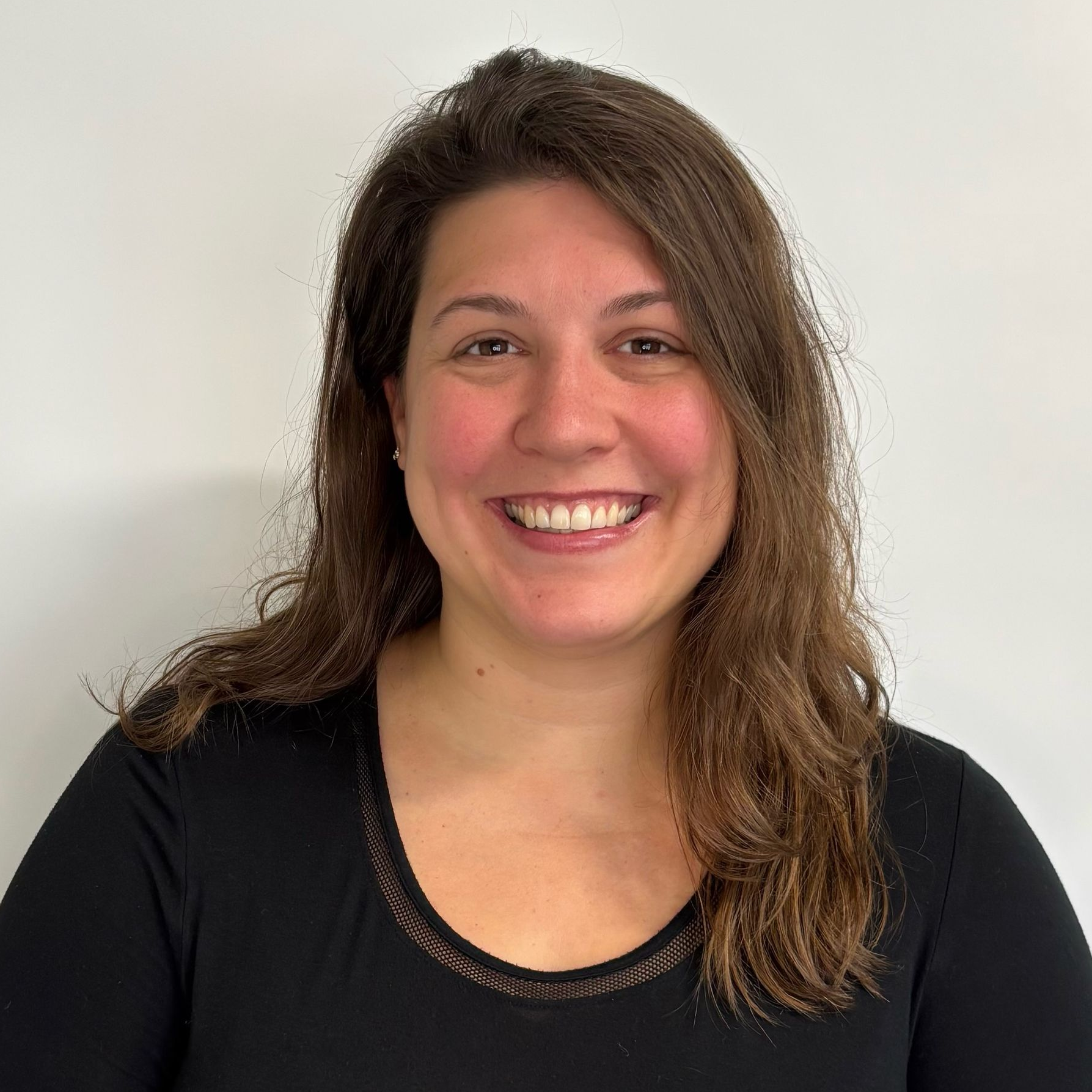 A woman in a brown sweater is smiling for the camera.