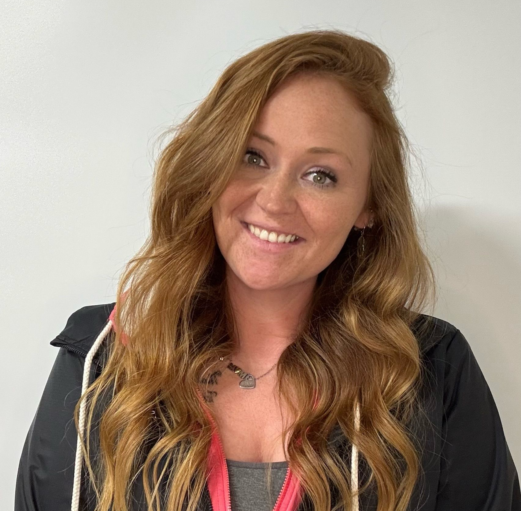 The woman is wearing a white sweater and smiling for the camera.