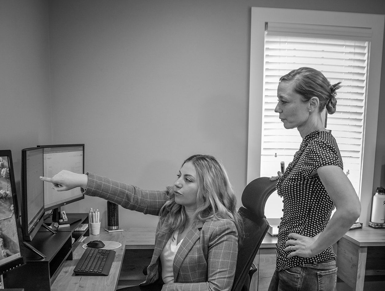 Two women are looking at a computer screen in a black and white photo.