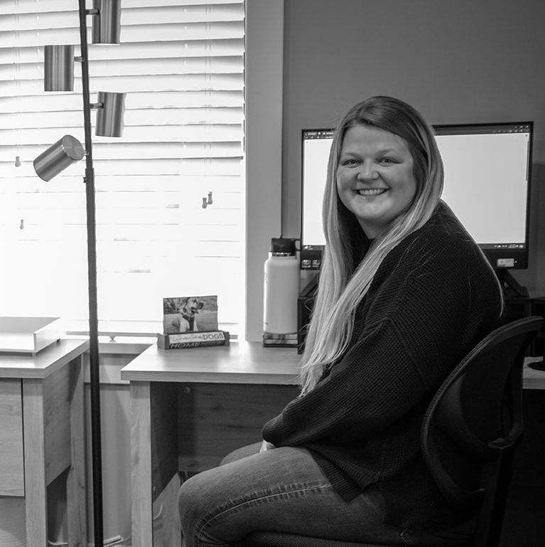 A woman is sitting at a desk in front of a computer.