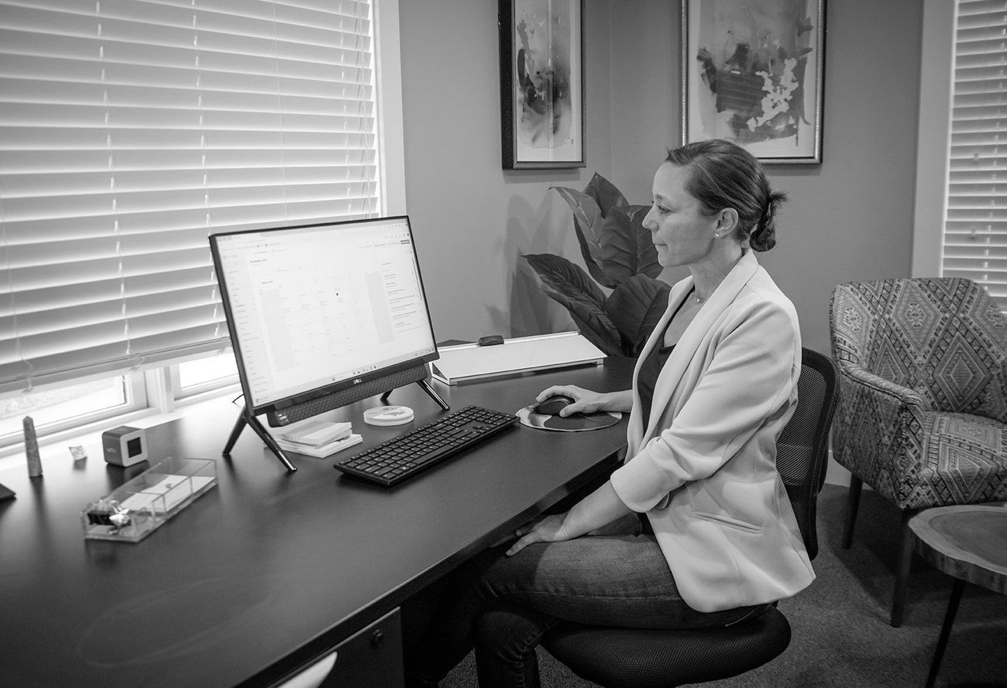 A woman is sitting at a desk in front of a computer.
