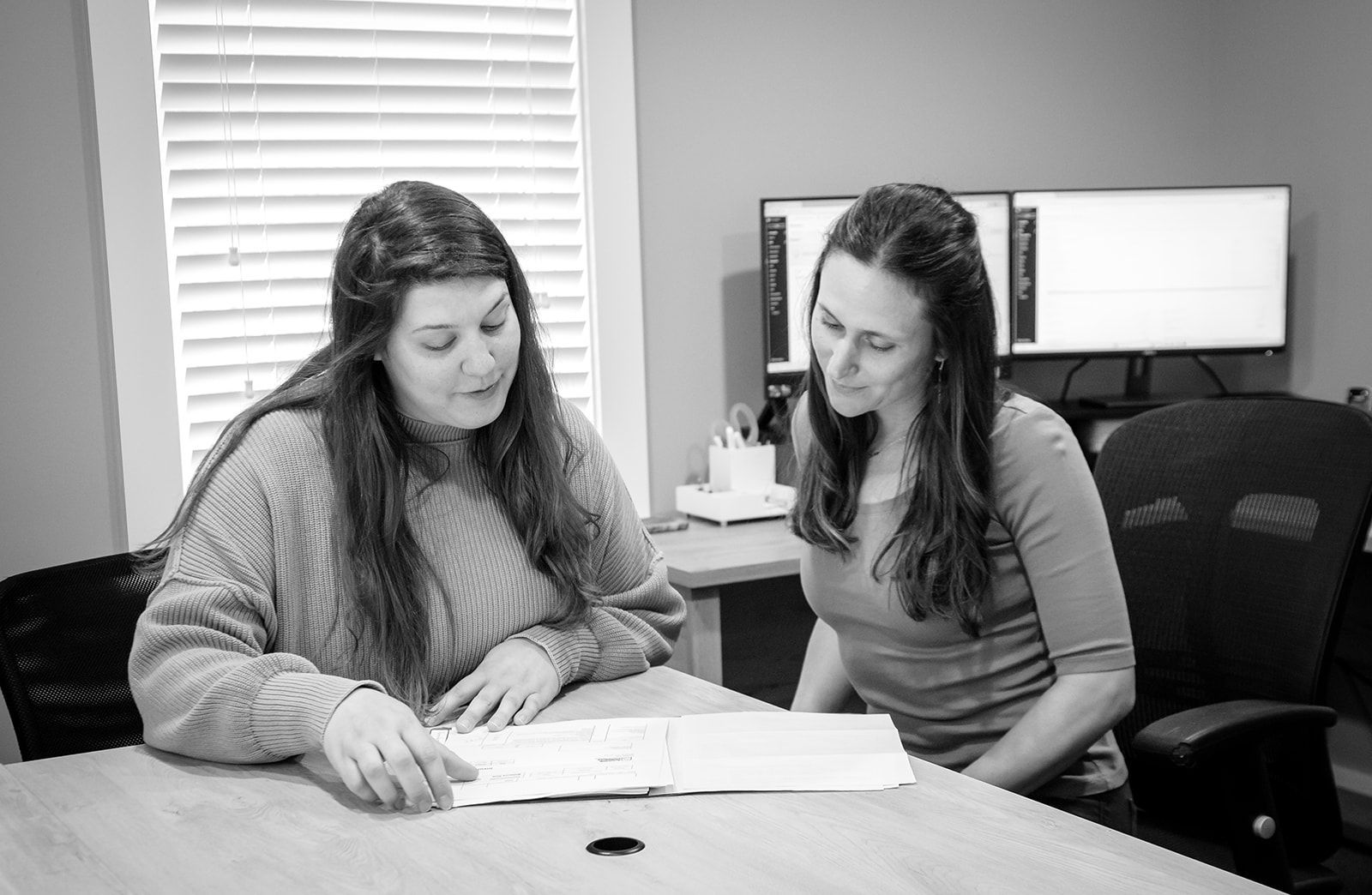 Two women are sitting at a table looking at a piece of paper.