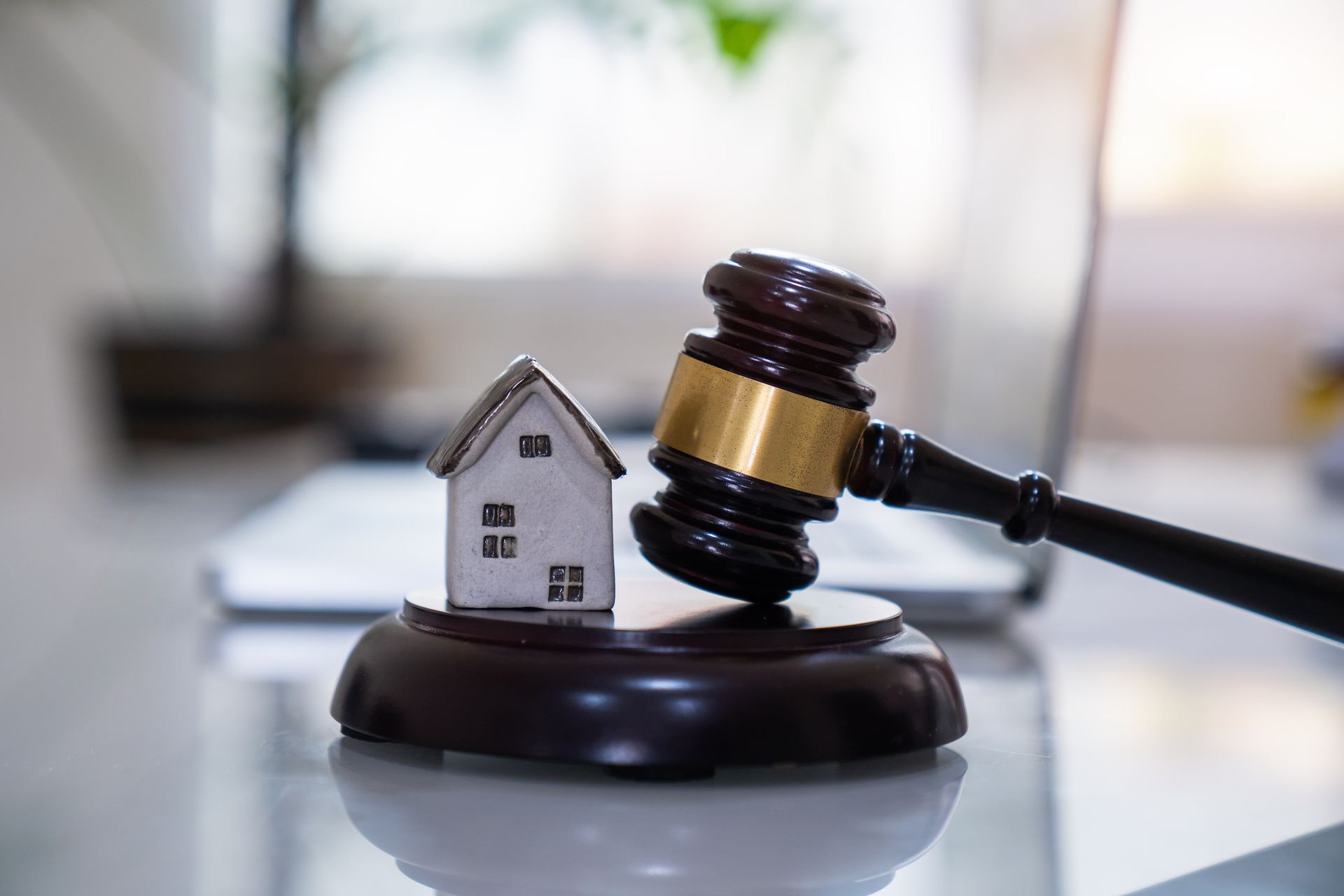 Judge’s gavel next to small house model on a desk.