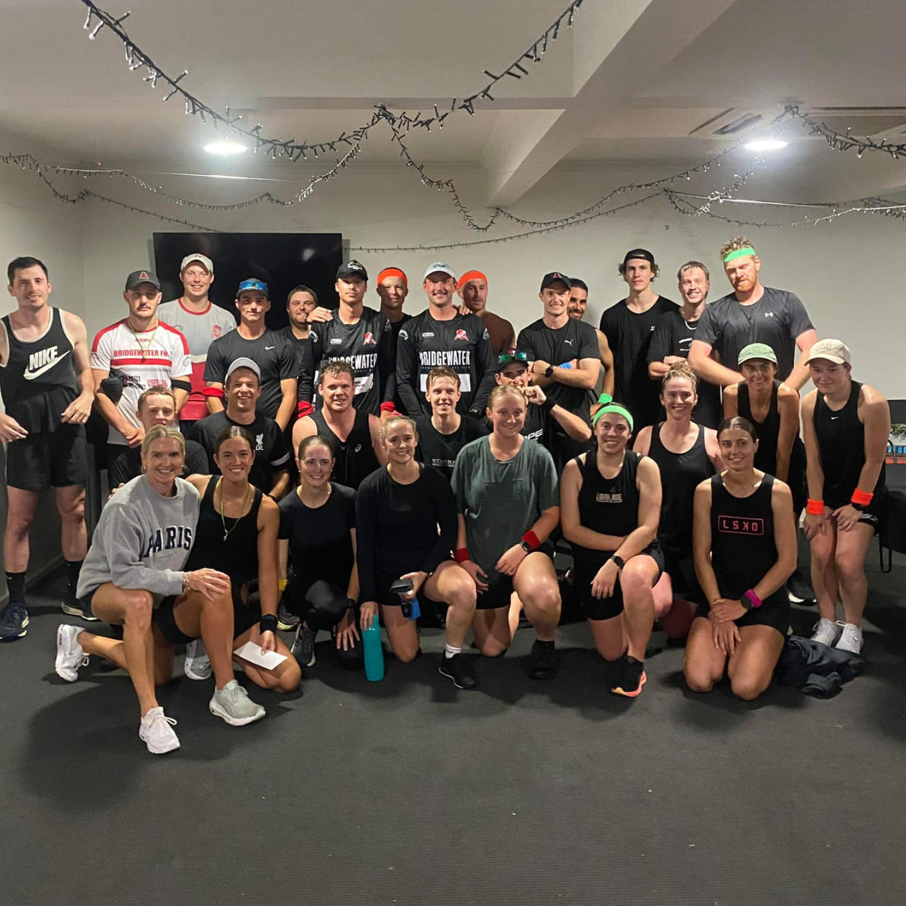 A large group of people are posing for a picture in a gym.