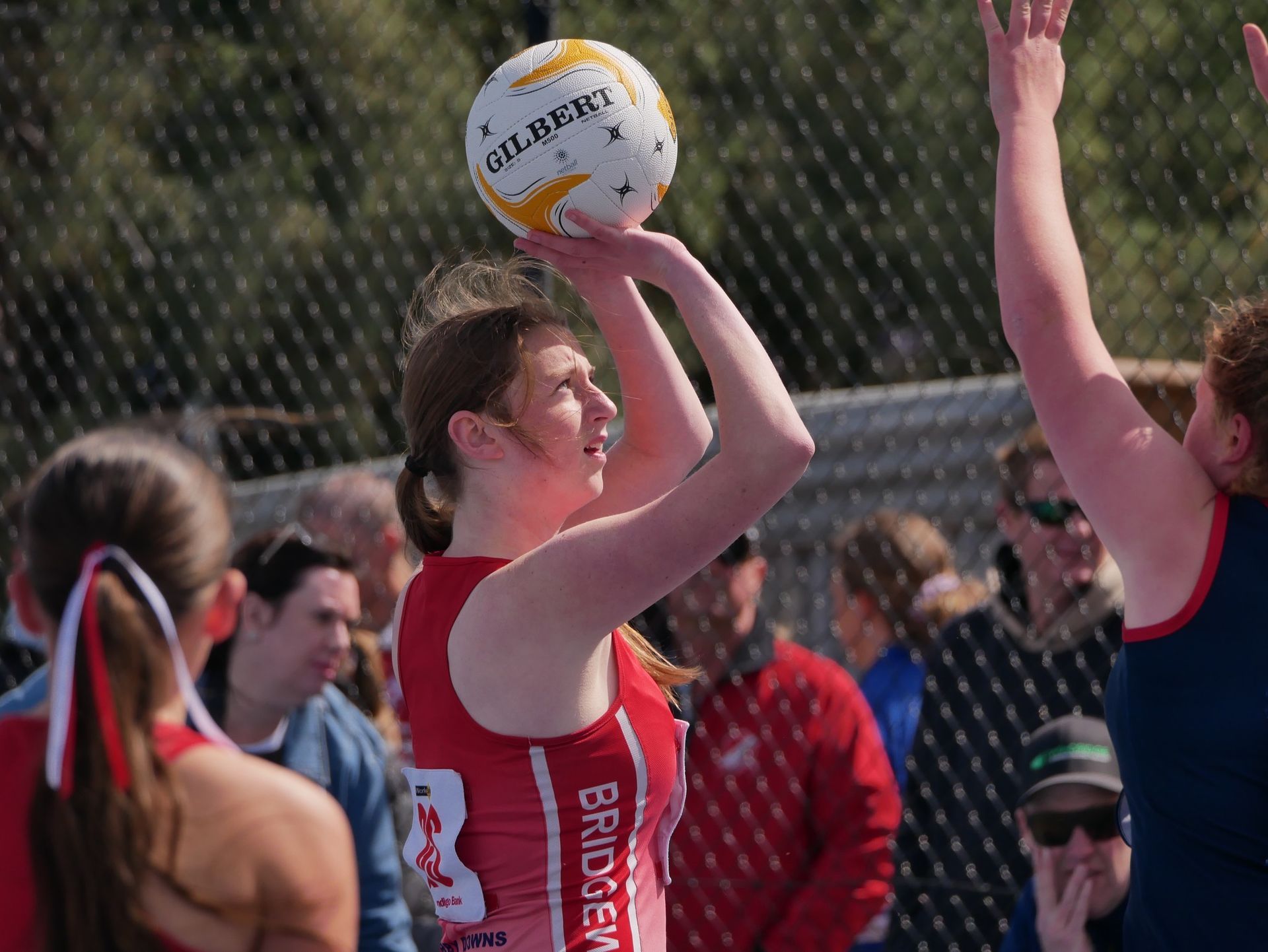 A woman in a red jersey is holding a volleyball in her hands.