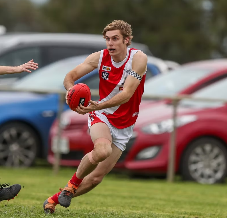 A man in a red and white jersey is running with a soccer ball