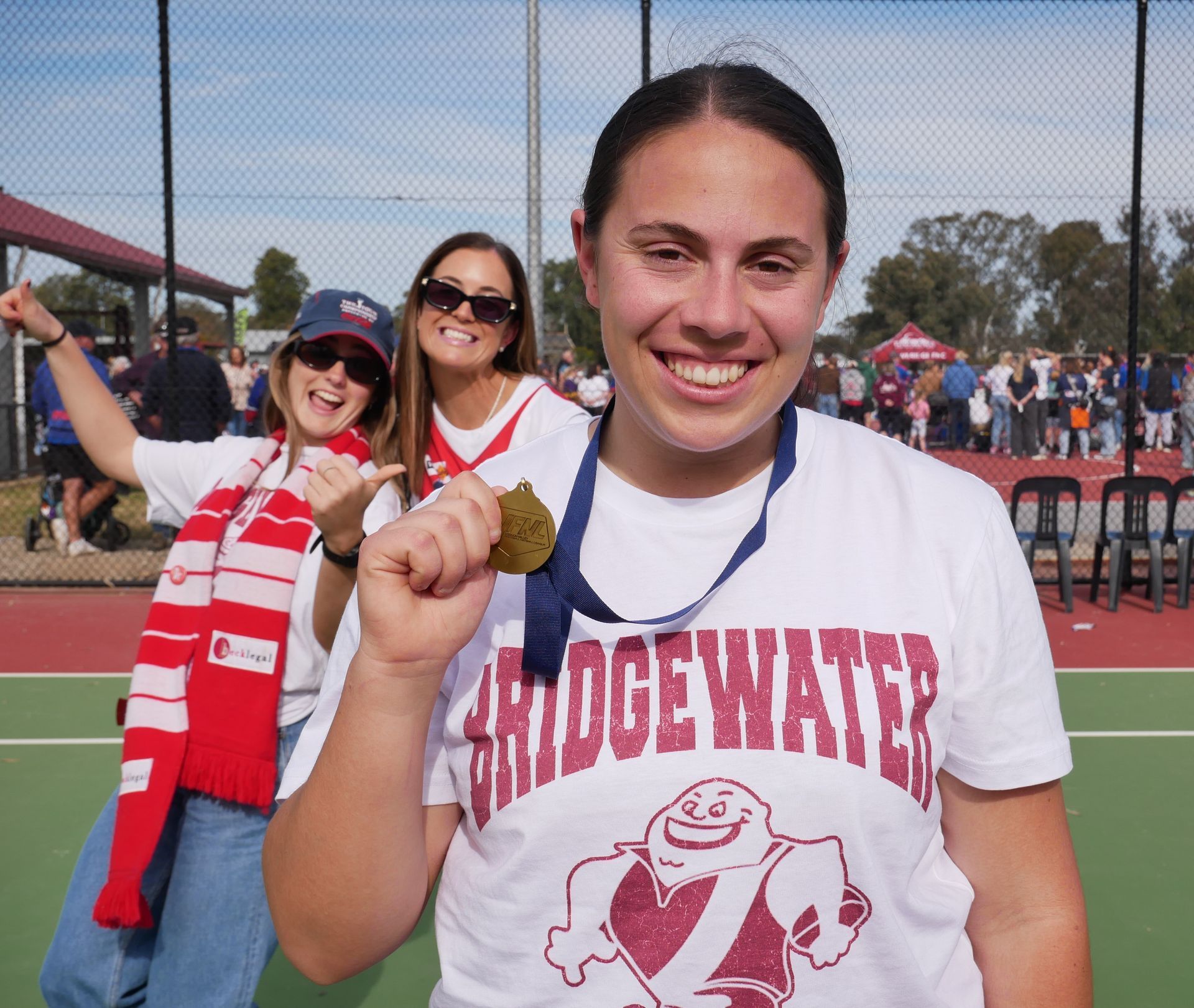 A woman in a red jersey is holding a gilbert netball
