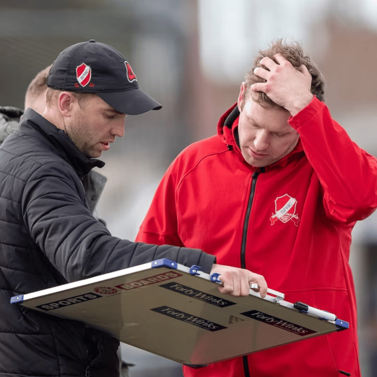A man in a red jacket is holding a piece of paper that says ' emergency ' on it