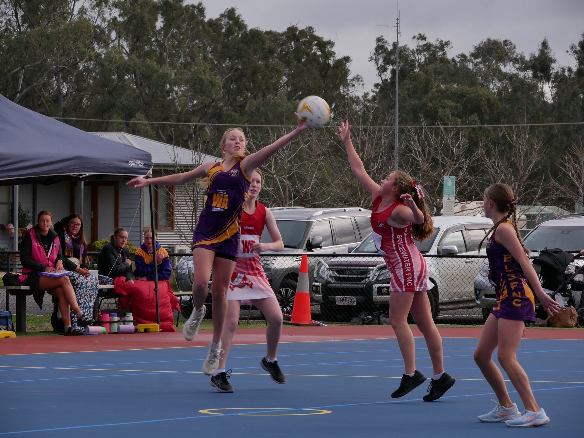 A group of young girls are playing netball on a court.
