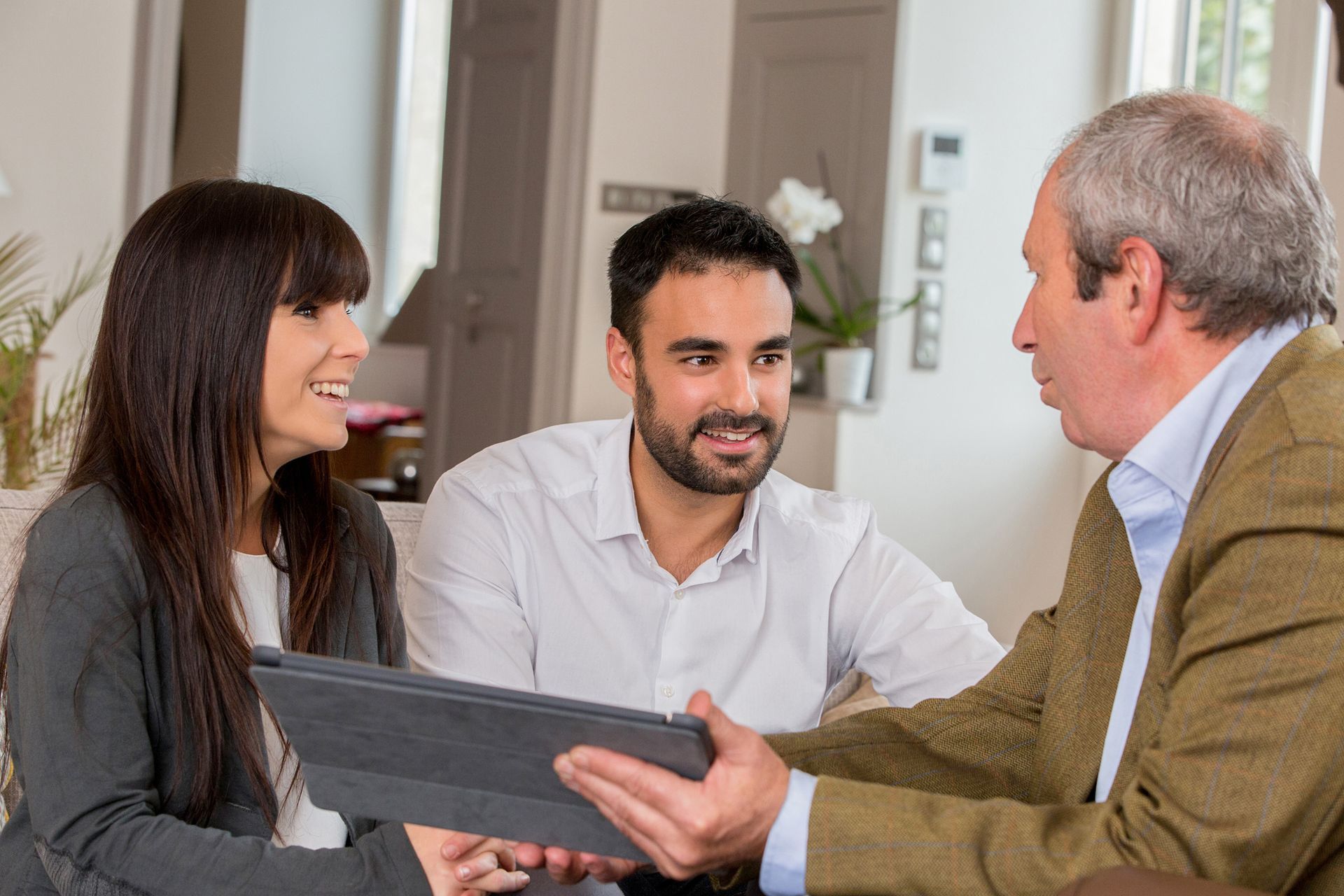 A local insurance agent in consultation with two clients at their home. A local insurance agent in consultation with two clients at their home.