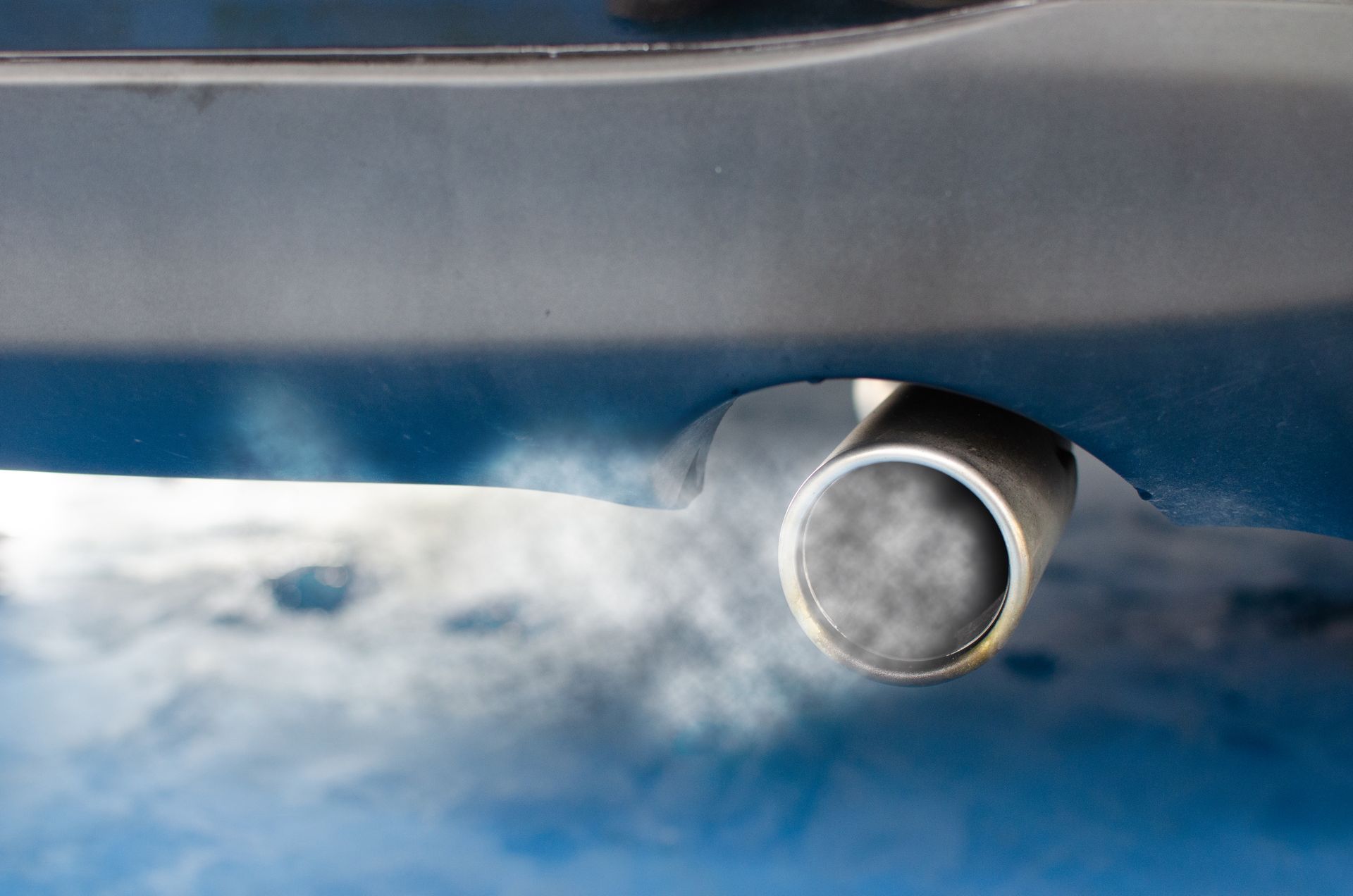 Exhaust pipe emitting smoke from a blue car.