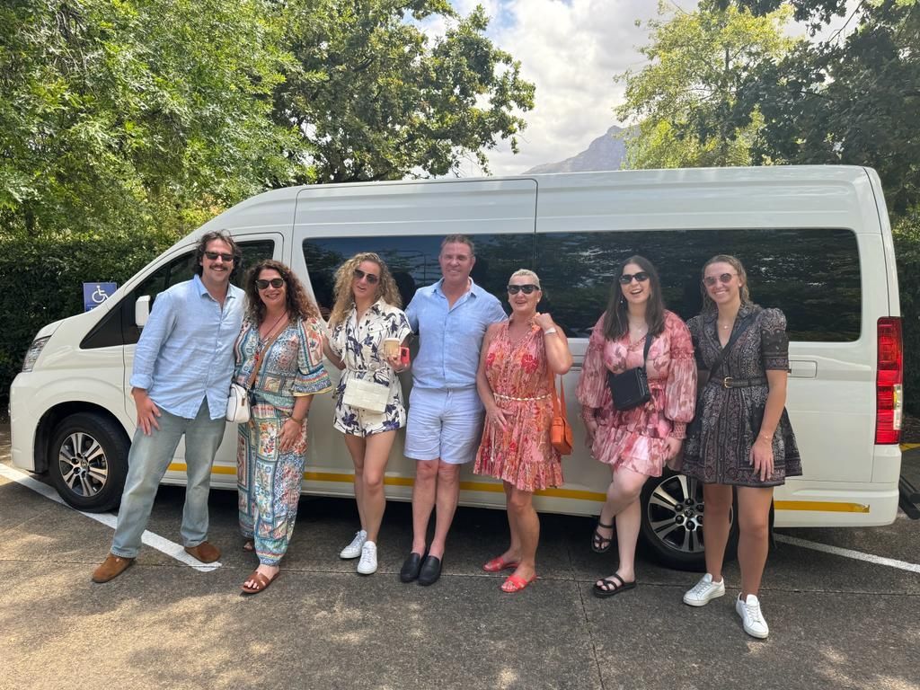 A group of people are standing in front of a white van.