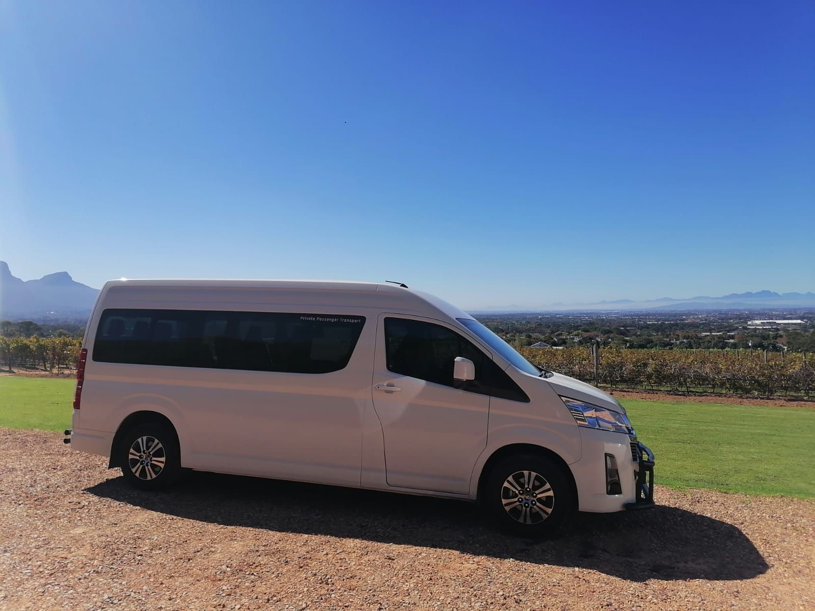 A white van is parked on a gravel road in a field.