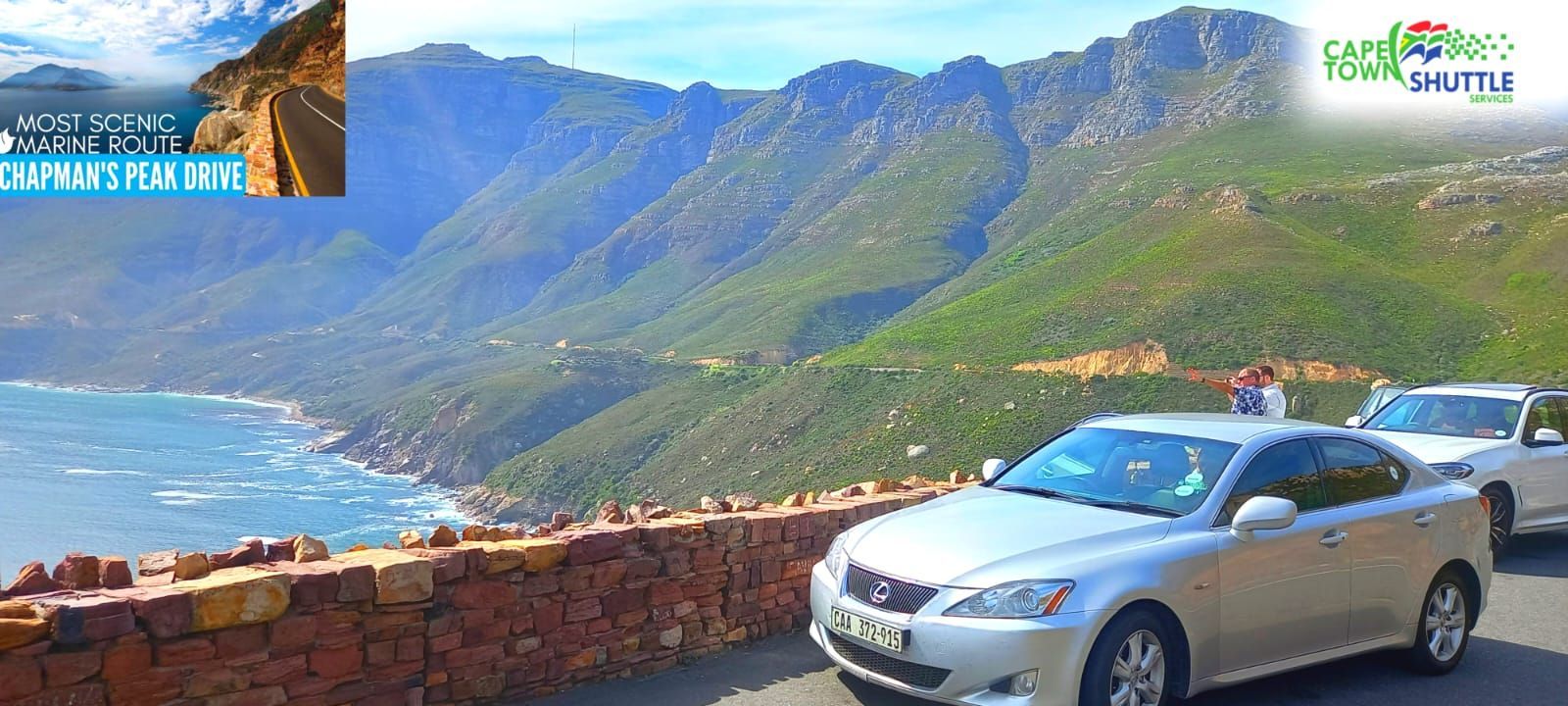 A silver car is parked on the side of a road next to a mountain.
