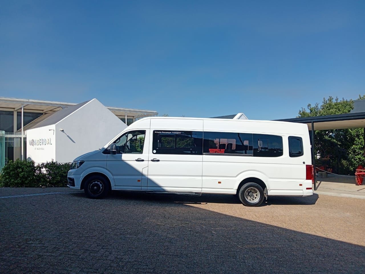 A white van is parked in a parking lot in front of a building.