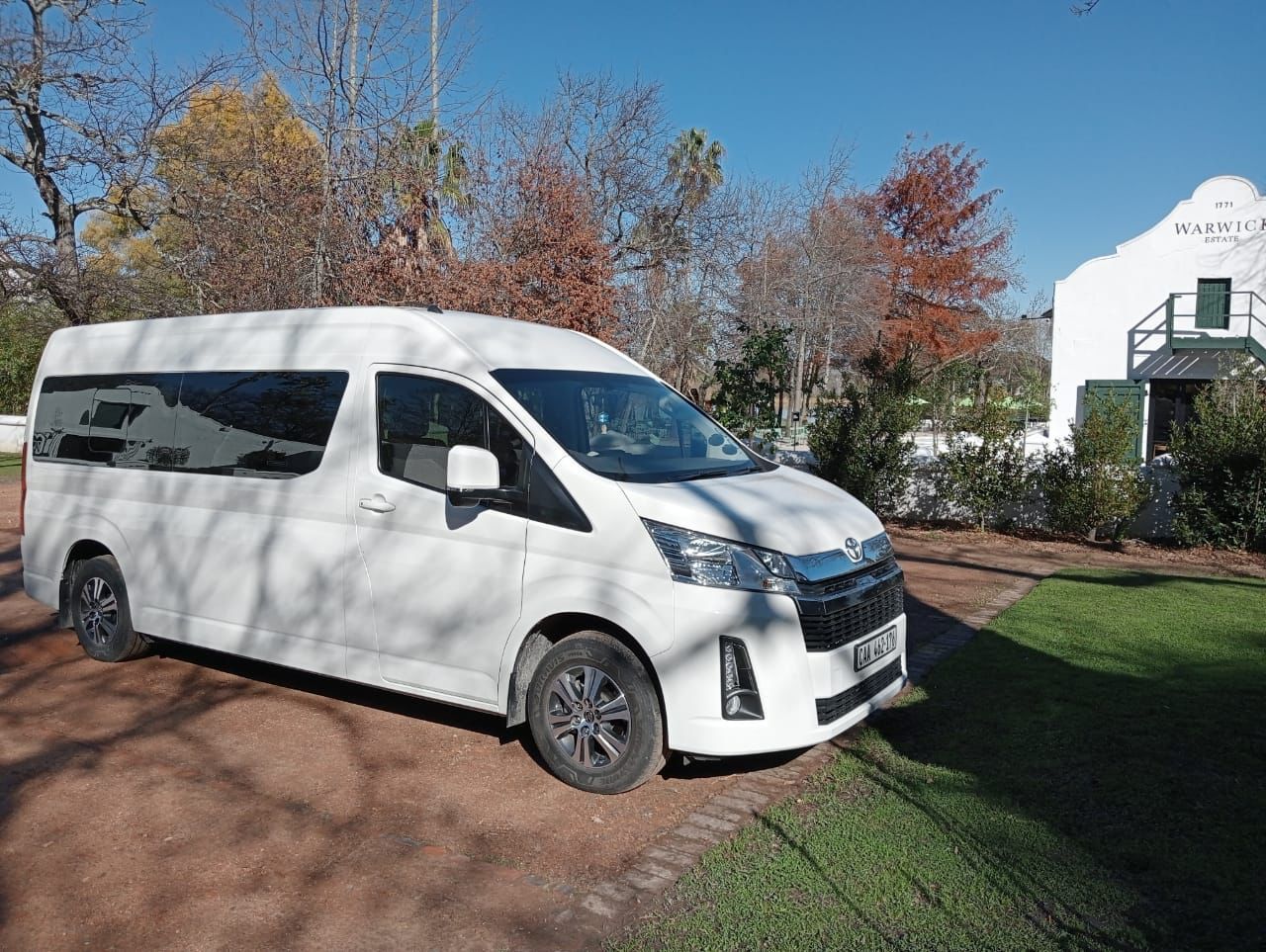 A white van is parked in front of a white house.