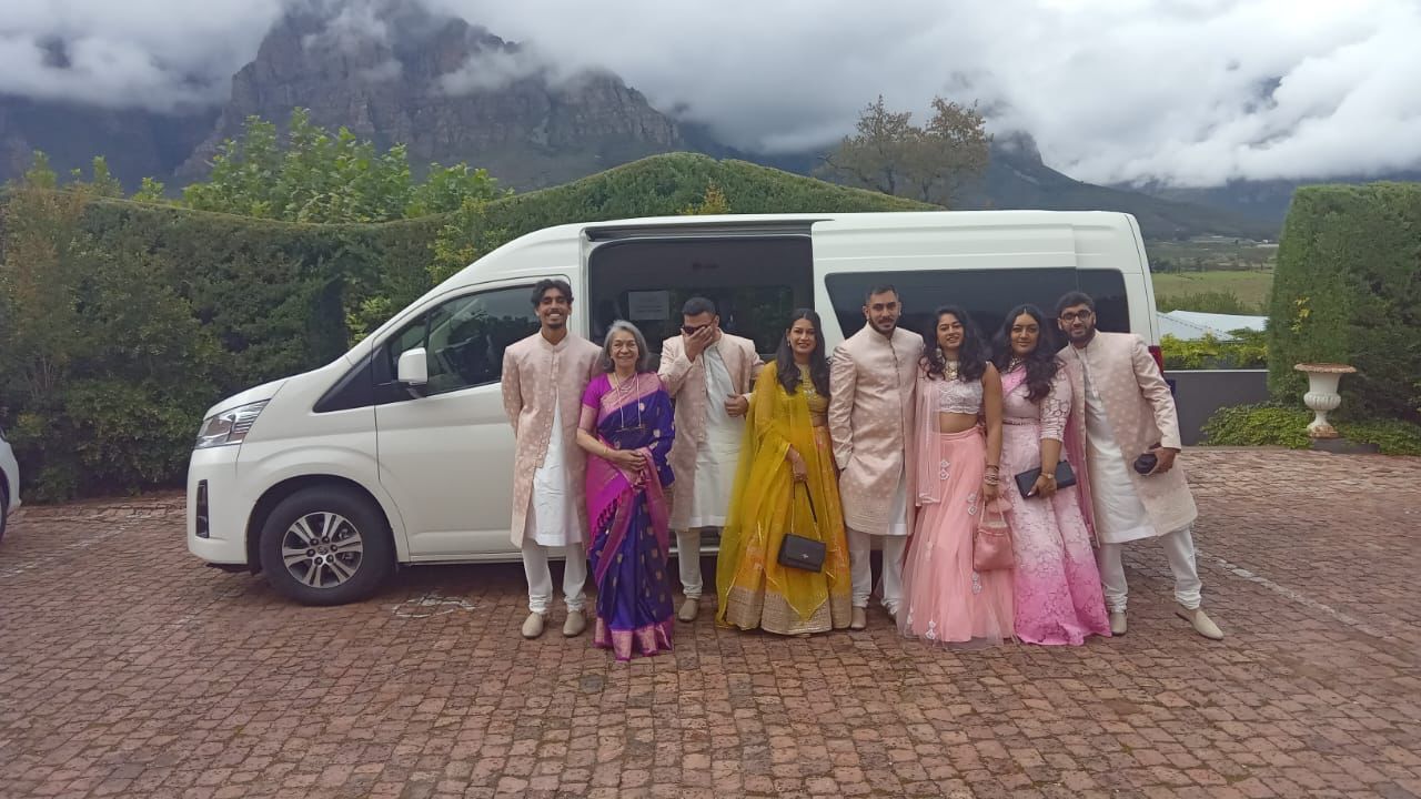A group of people are posing for a picture in front of a white van.