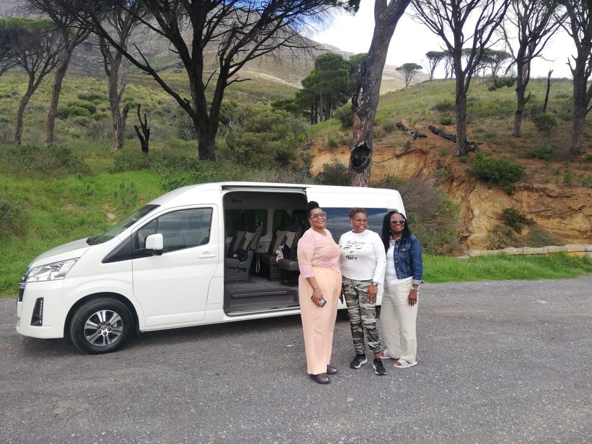 Three women are standing in front of a white van.