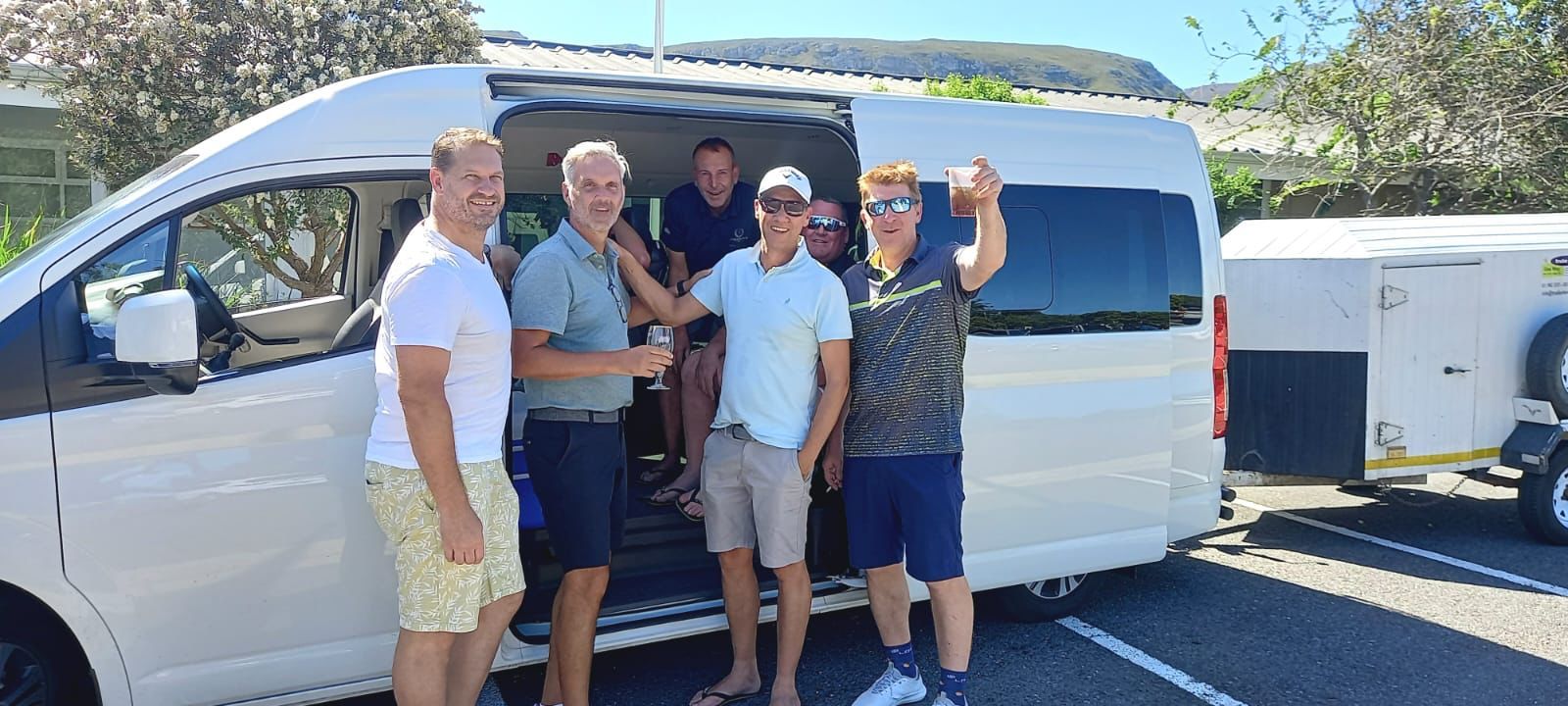 A group of men are standing in front of a white van.