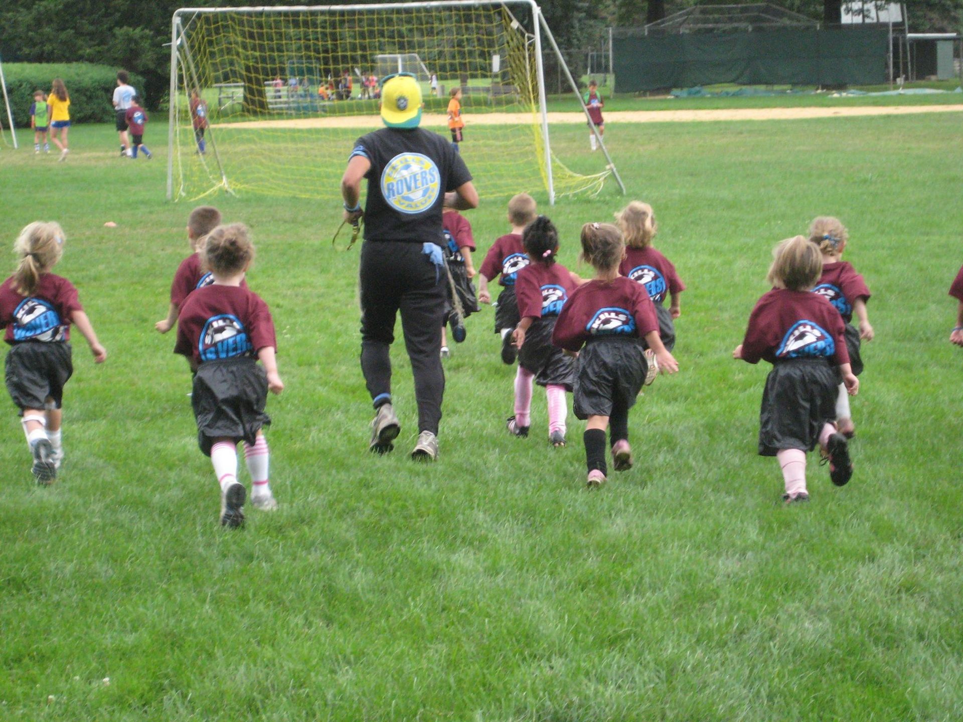 a group of children are running on a soccer field