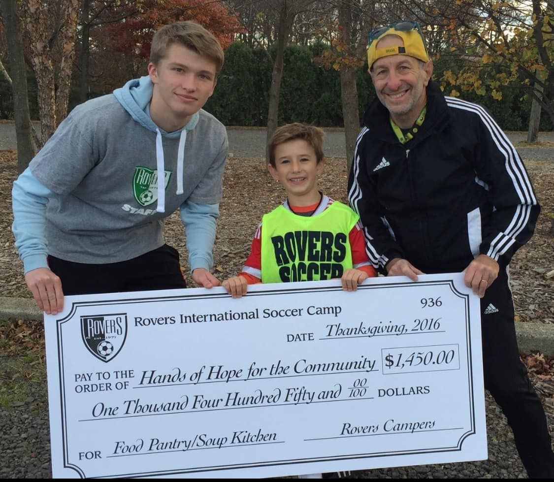 a boy in a yellow shirt that says bowers soccer is holding a check