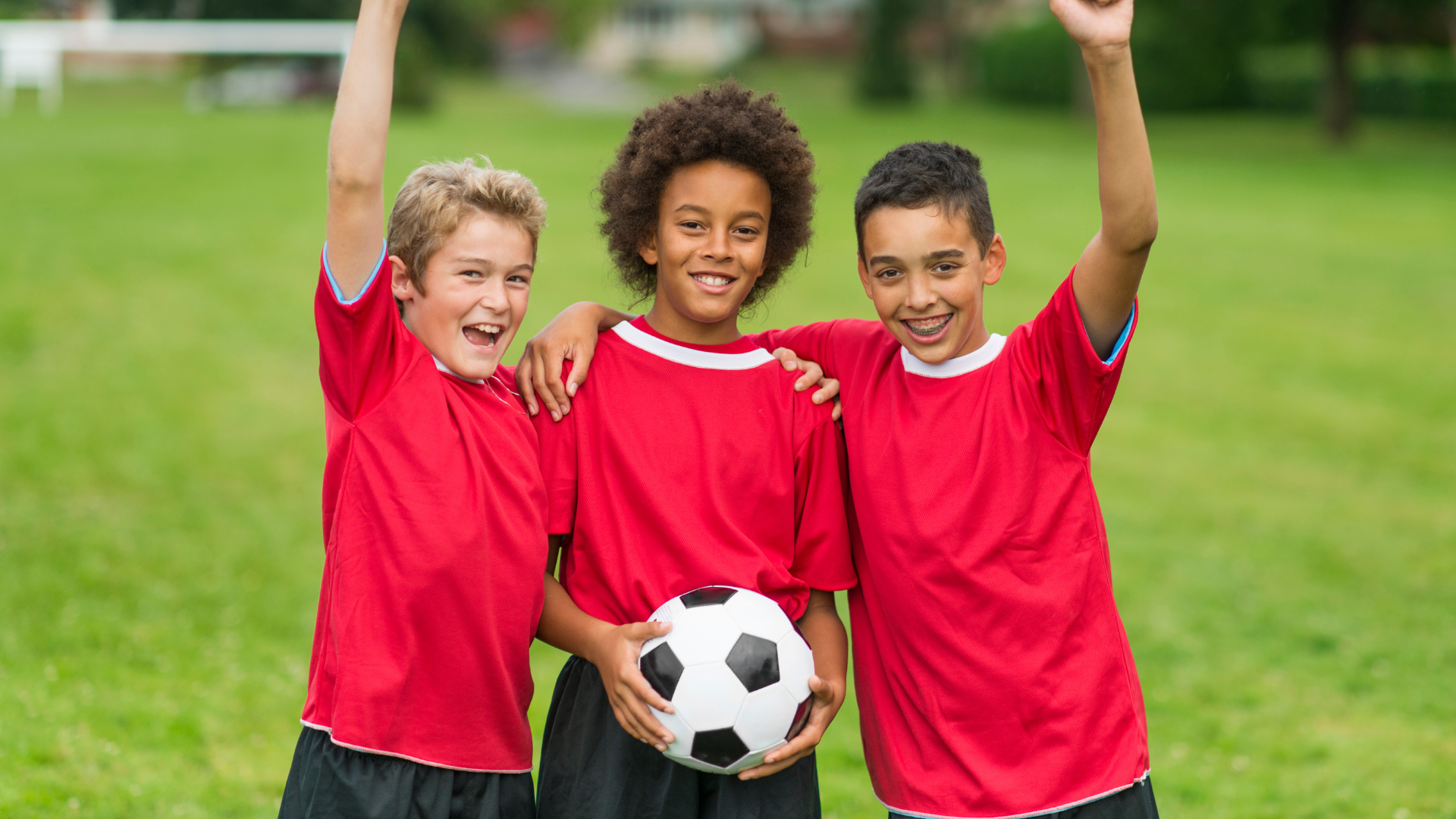 a young boy is holding a soccer ball over his head .