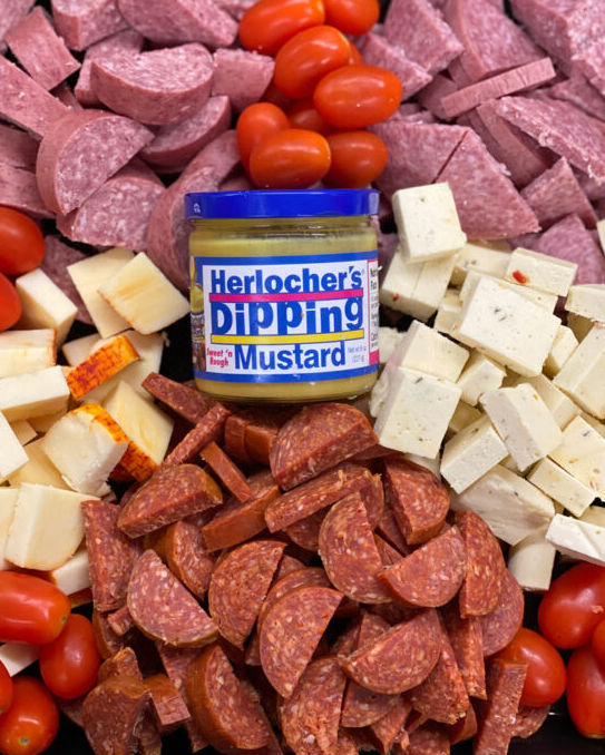 A jar of herlocher 's dipping mustard surrounded by meats and cheese