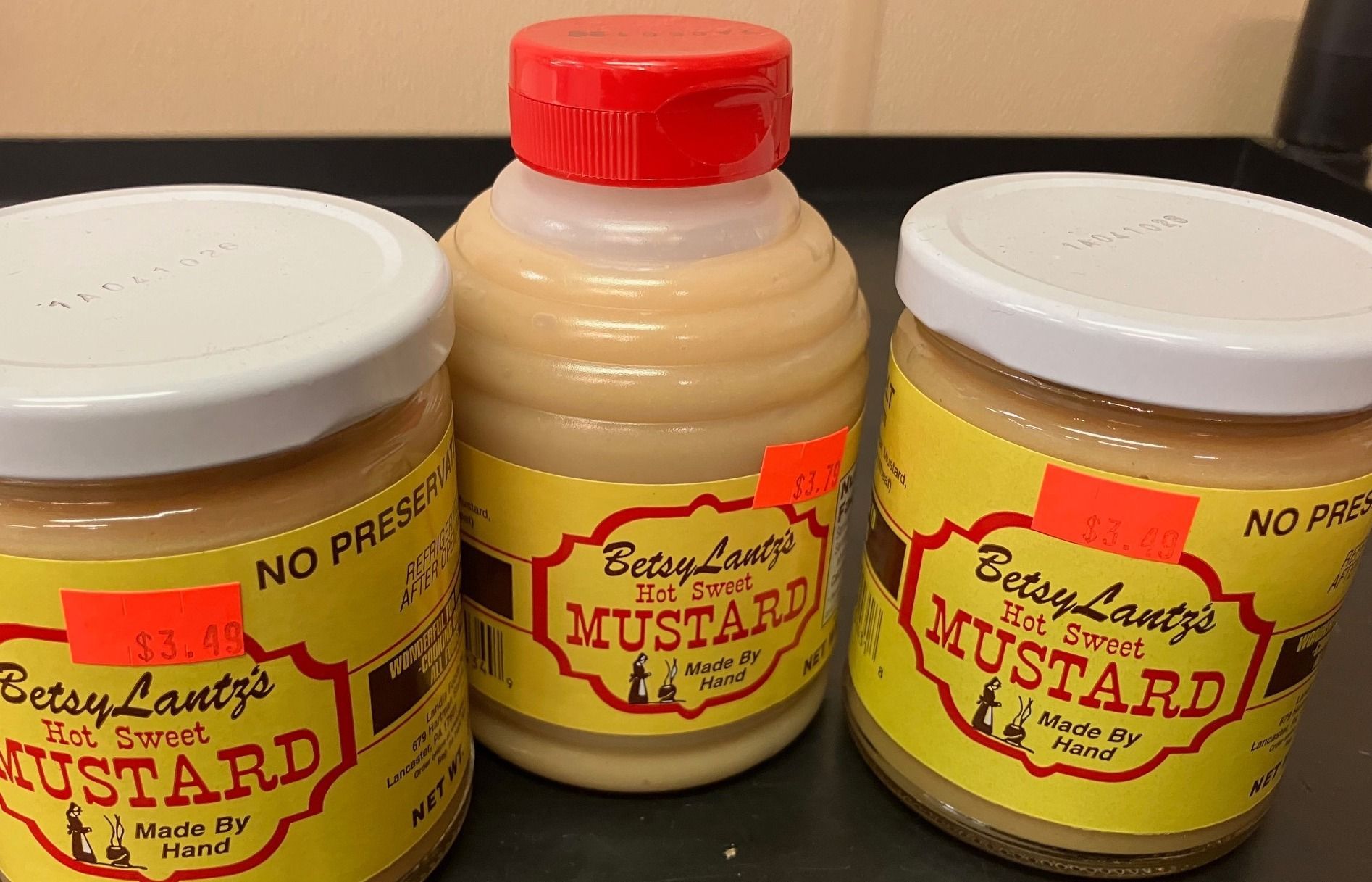 Three jars of mustard are sitting on a table