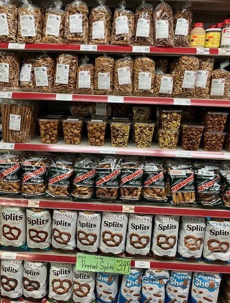 A grocery store aisle filled with bags of pretzels , nuts , and other snacks.