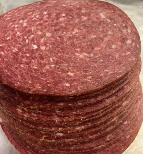 A close up of a stack of salami slices on a table.