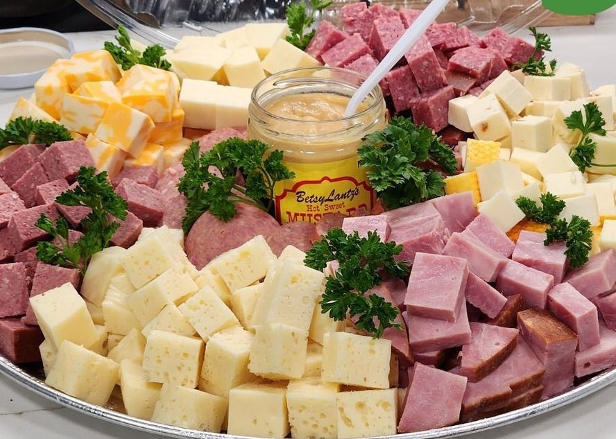 A jar of herlocher 's dipping mustard surrounded by meats and cheese