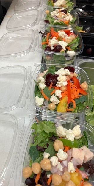 A bunch of plastic containers filled with fruit are stacked on top of each other on a table.