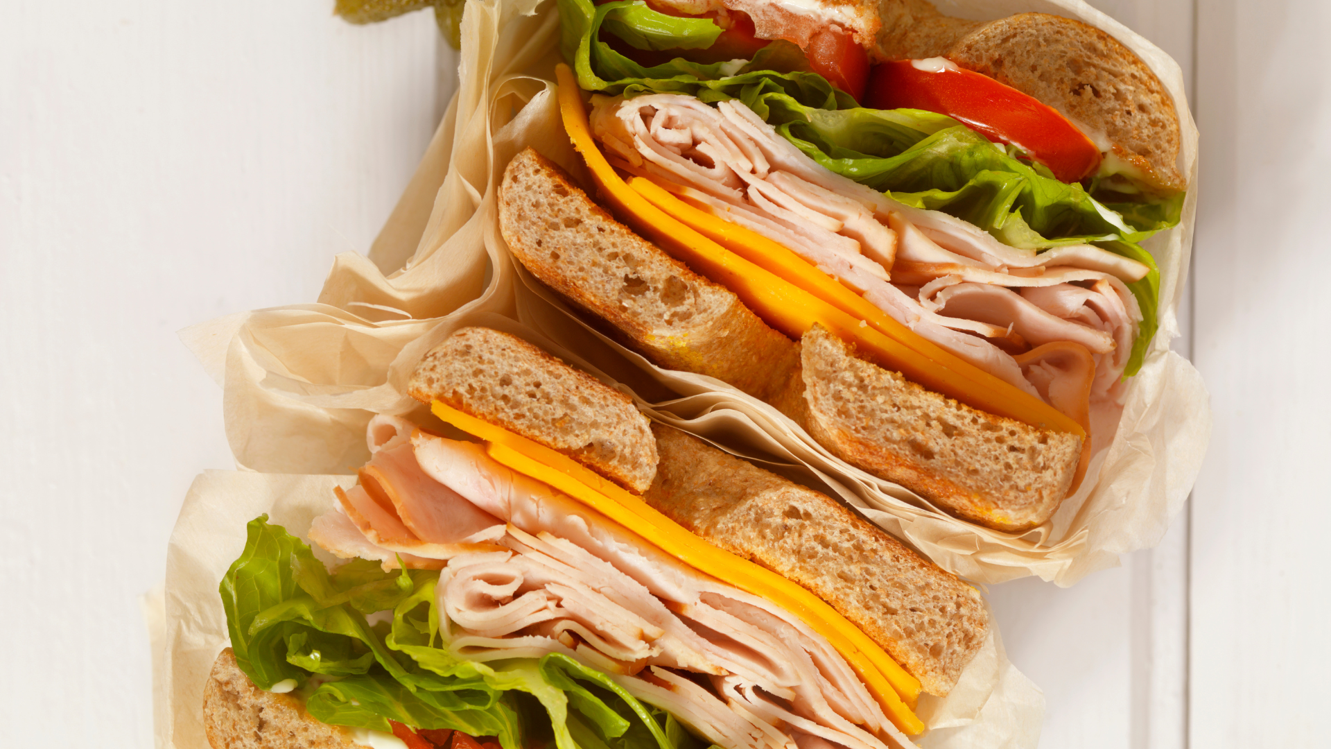 Three sandwiches are stacked on top of each other on a white plate.