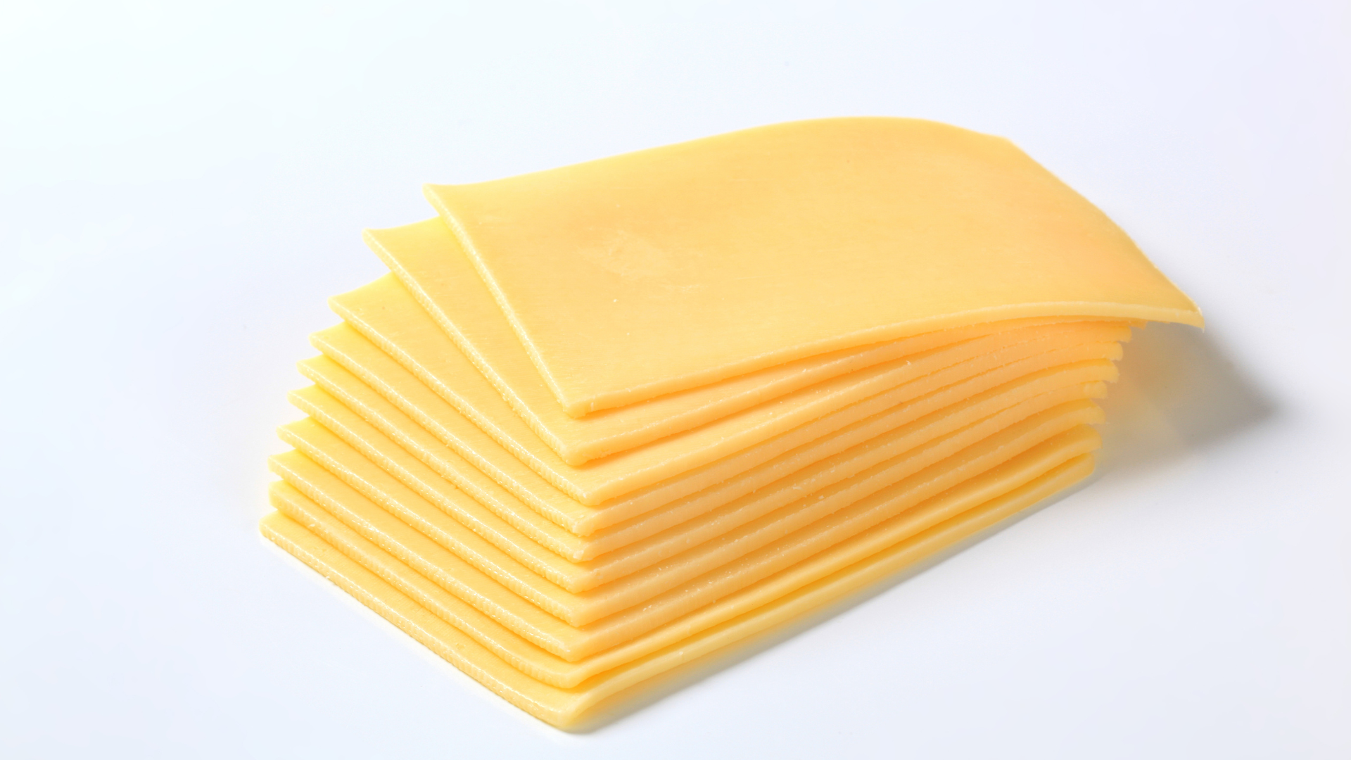 A stack of sliced cheese on a white surface.
