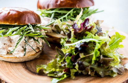 Two sandwiches and a salad on a wooden cutting board.