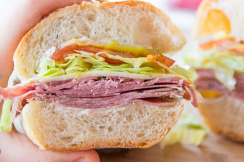 A person is holding a sub sandwich in their hand.