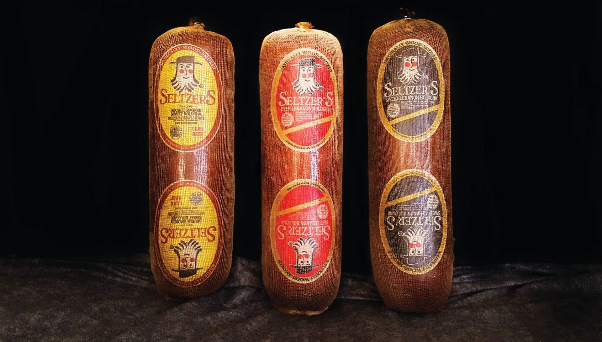 Three cylindrical sausages with colorful labels.
