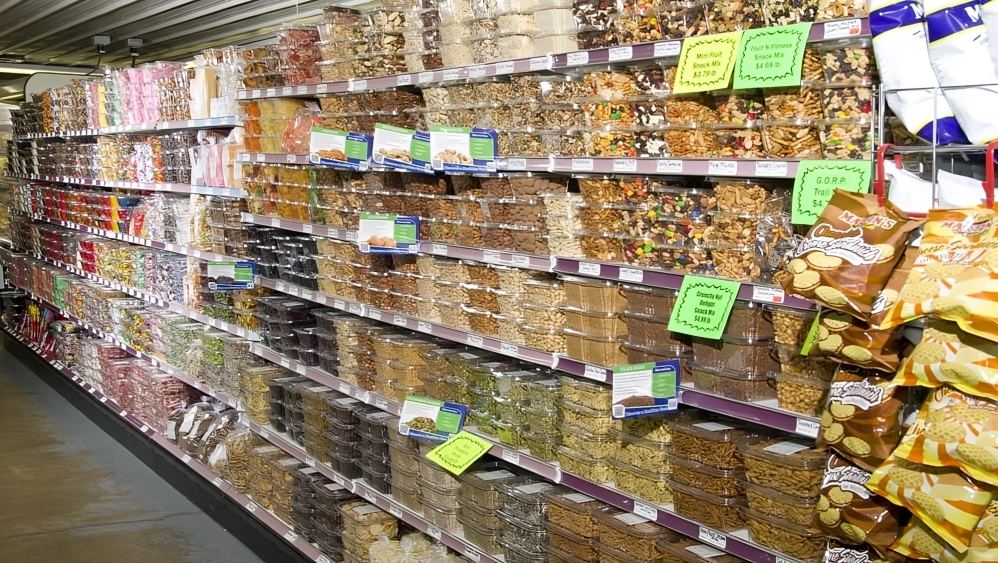 A grocery store aisle filled with bags of pretzels , nuts , and other snacks.