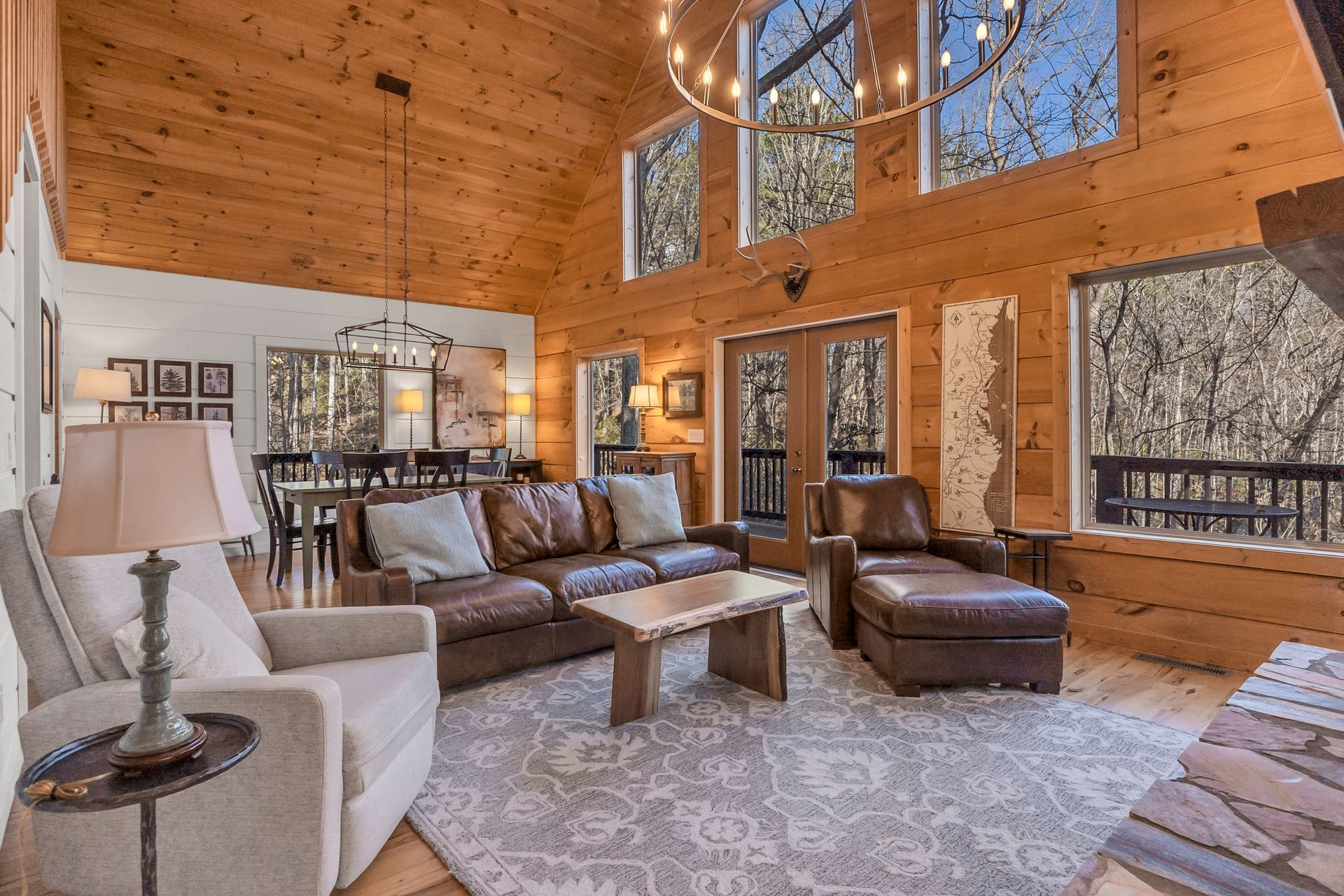 A living room in a log cabin with a lot of windows and furniture.