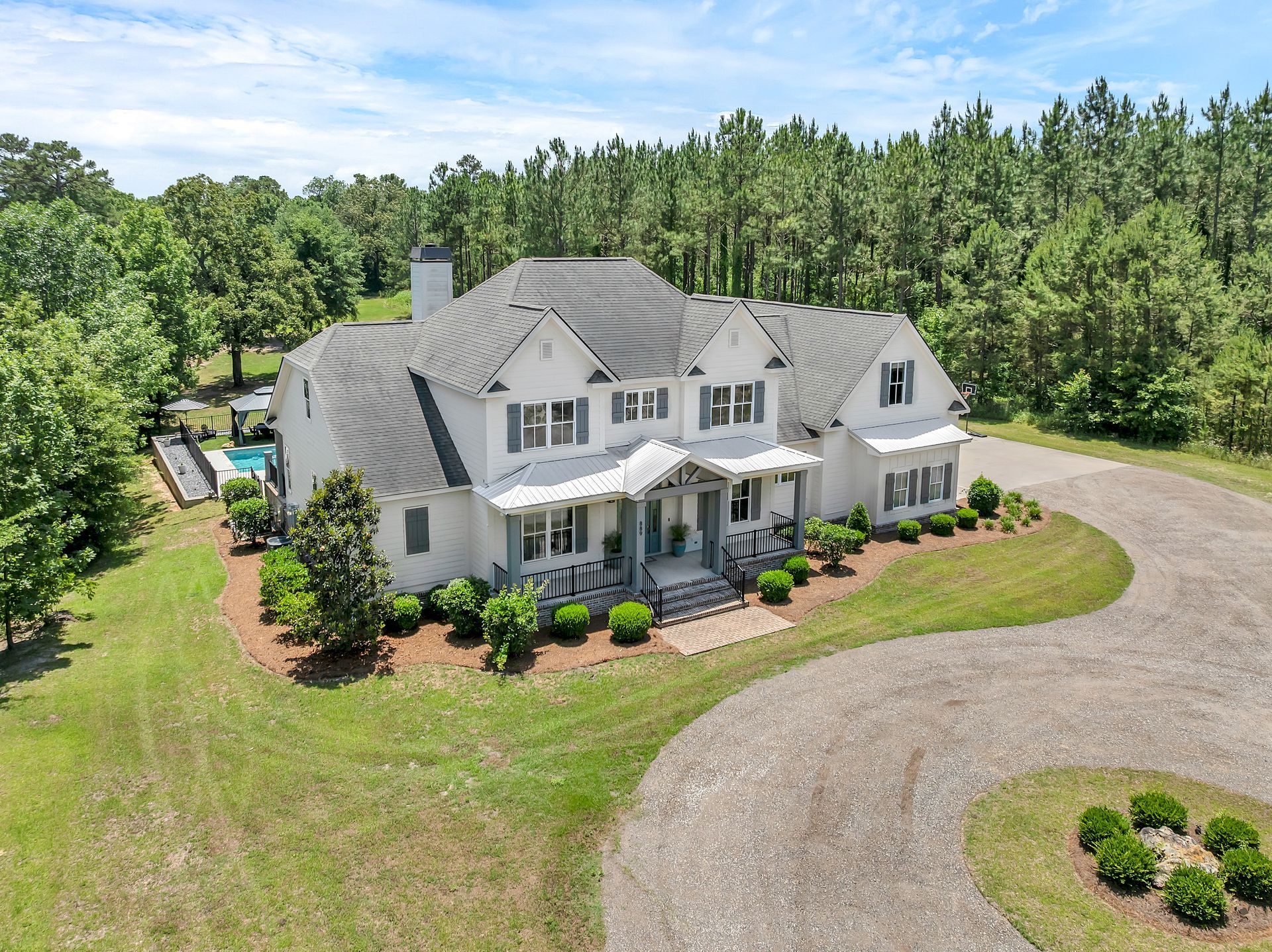 An aerial view of a large white house surrounded by trees and grass.