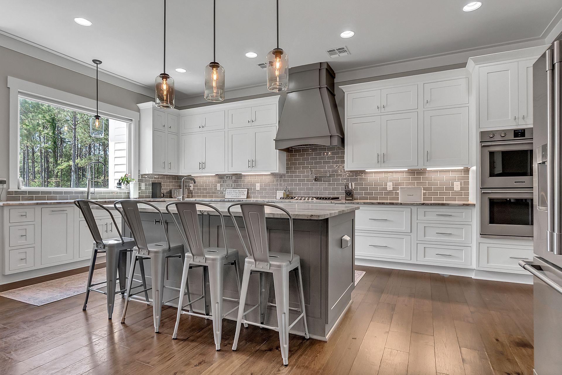 A kitchen with white cabinets and stainless steel appliances and a large island.
