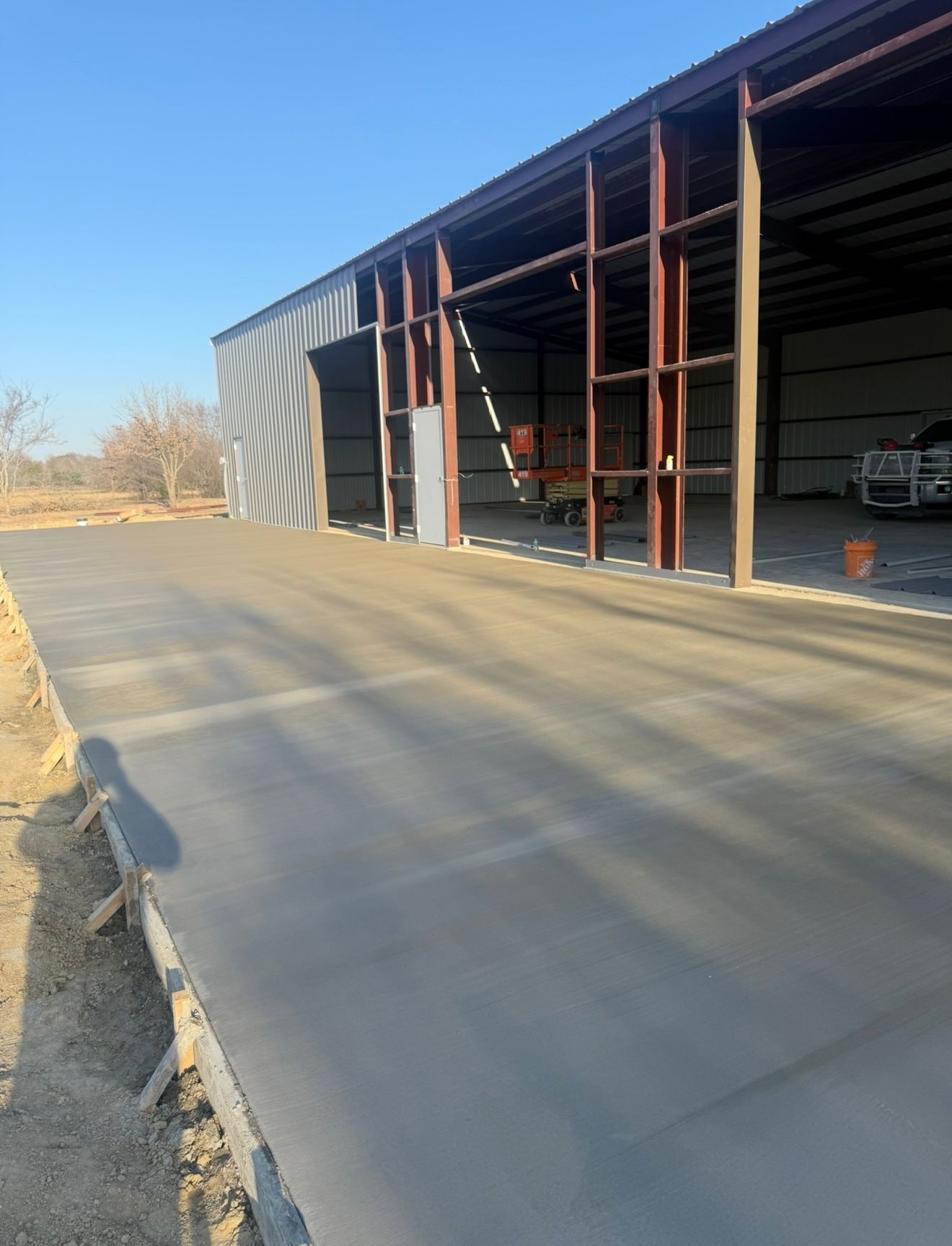Industrial building with open bays and a concrete driveway in the foreground