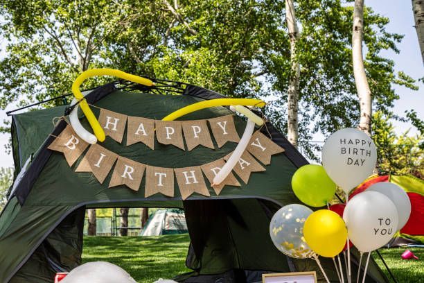 A green tent decorated for a birthday party with balloons and a