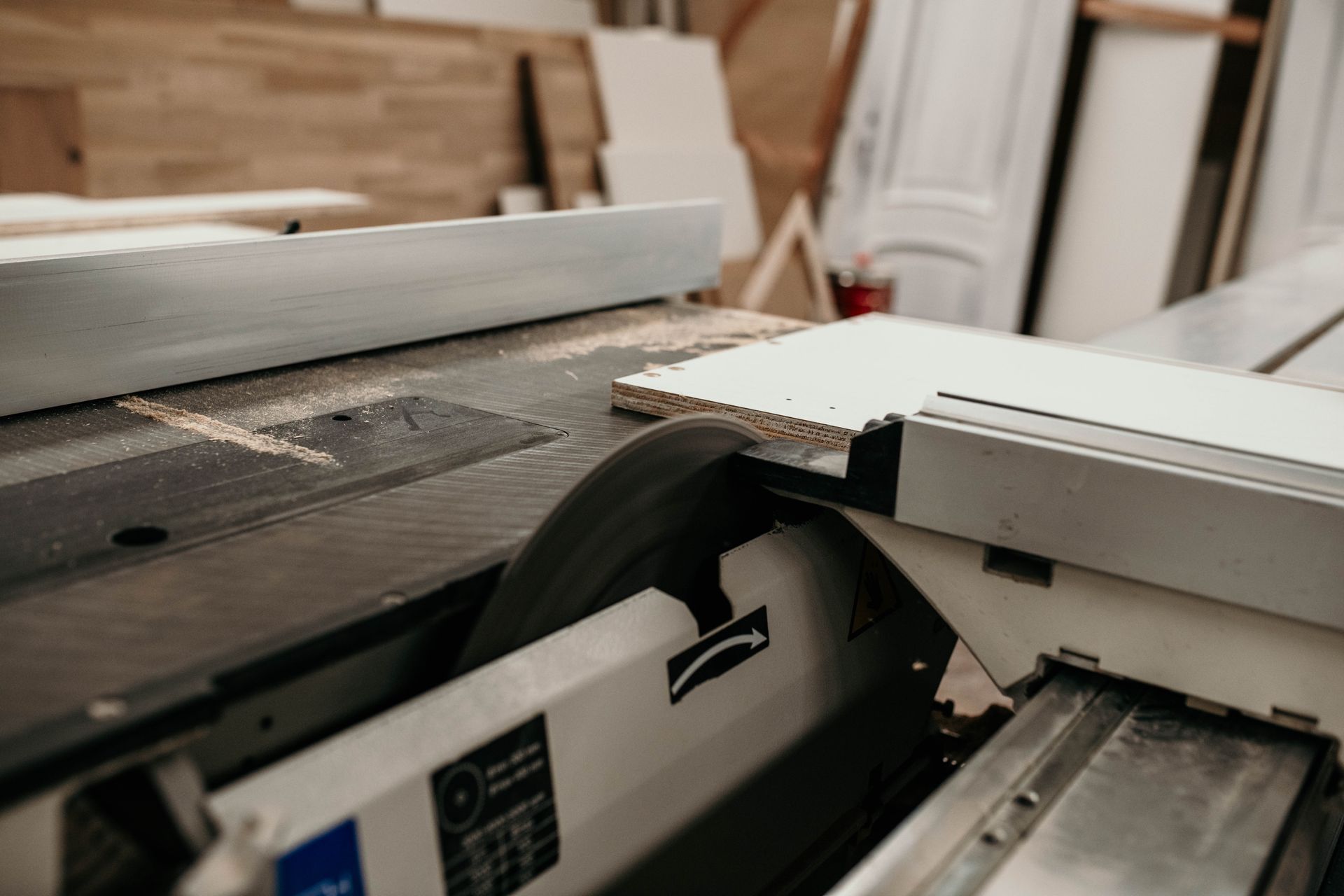 Una sega da tavolo bianca taglia il legno bianco in un'officina.
