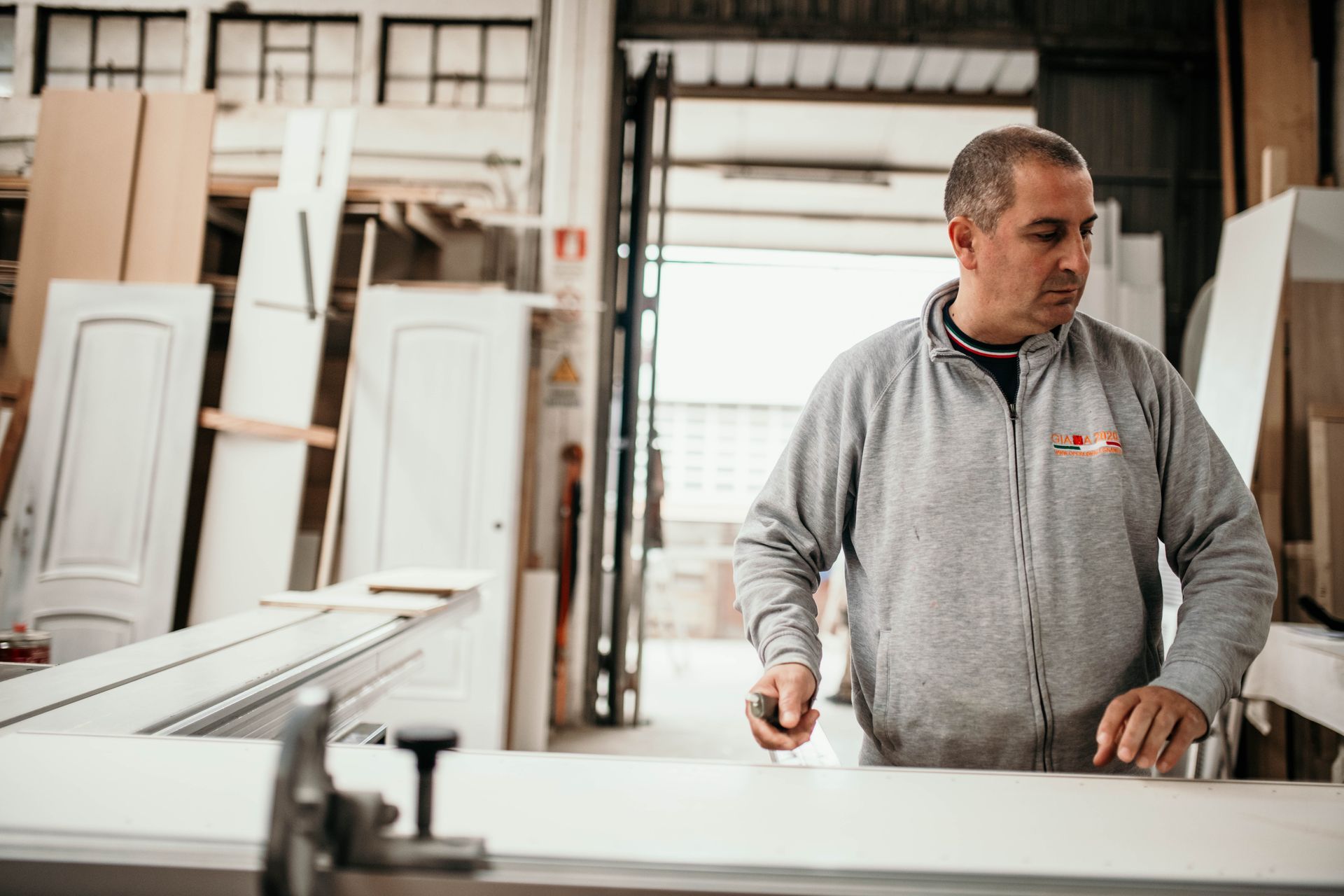 Un uomo in un'officina traccia un segno su un pannello bianco con una matita.