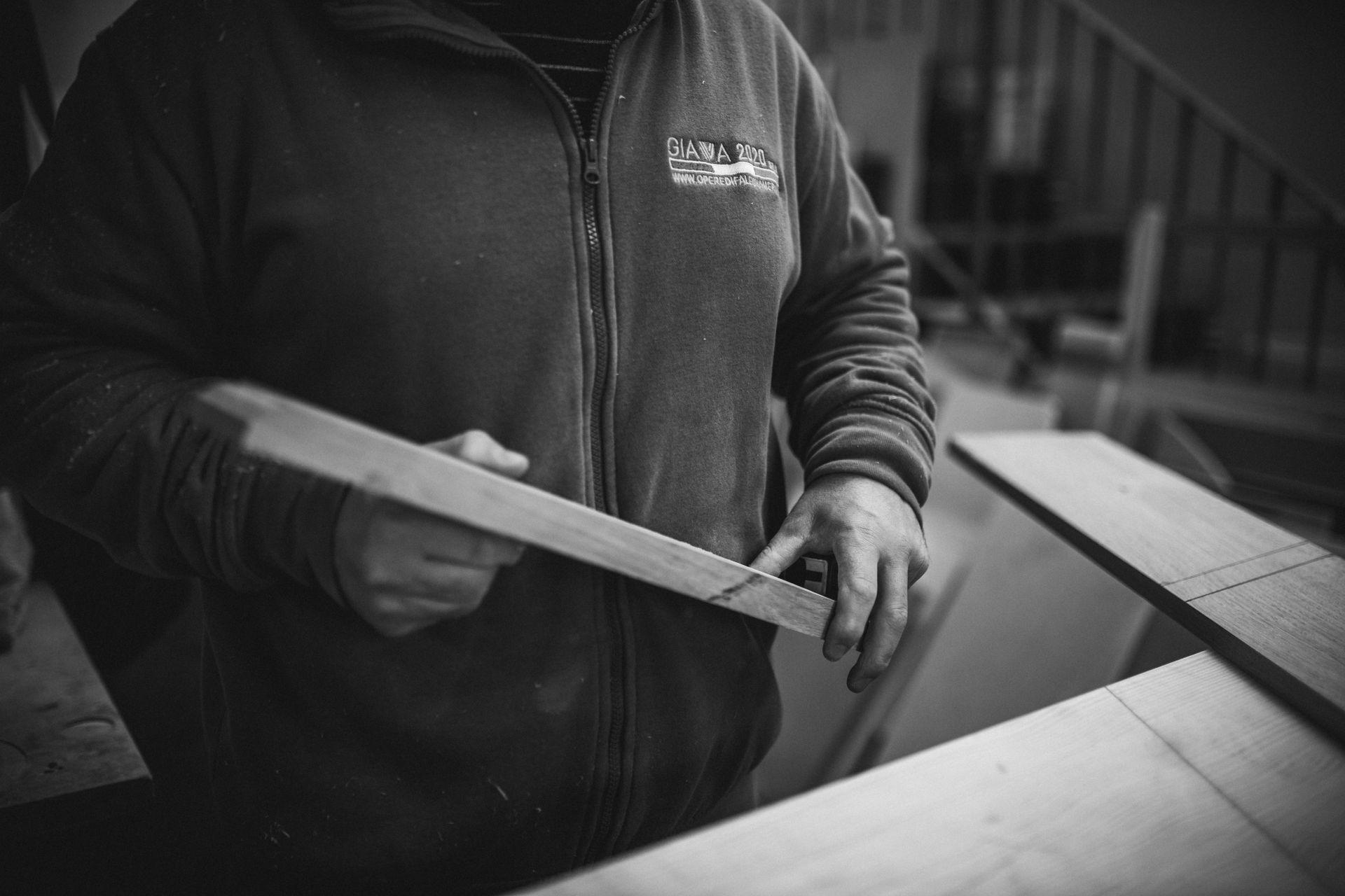 Una persona in un laboratorio esamina un'asse di legno, tenendola vicino a un tavolo.