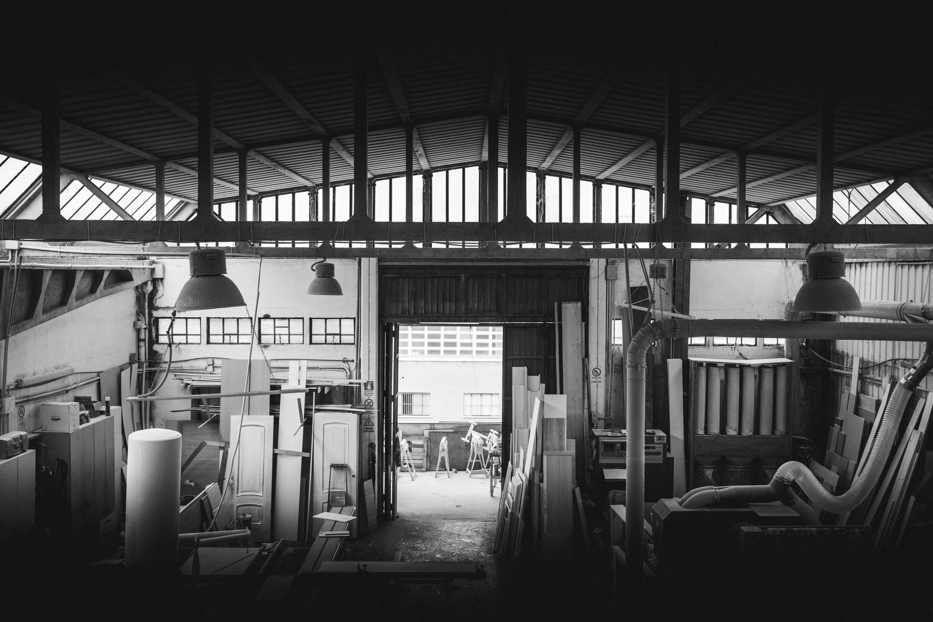 Foto in bianco e nero dell'interno di un'officina, con travi in legno e luci soffuse.